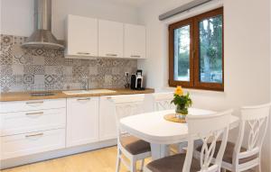 a kitchen with white cabinets and a white table and chairs at Lovely Home In Gruda With Wifi in Gruda