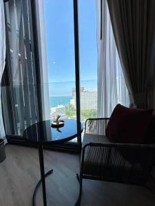 a living room with a table and a chair and a window at Edge centarl pattaya luxury sea view in Ban Khok Kham