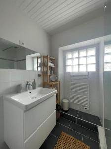 a white bathroom with a sink and a mirror at Maison de pêcheurs a 100m de l'océan! in Étel