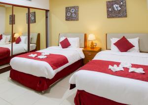 Una habitación de hotel con dos camas con sábanas rojas y blancas. en Al Liwan Residence, en Doha