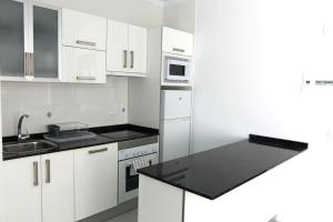 a kitchen with white cabinets and a black counter top at Costa Mar Sea View in Puerto del Carmen