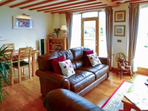 a living room with a leather couch and a table at Wold View Cottage in Rillington