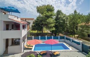 ein Pool mit zwei Sonnenschirmen und ein Gebäude in der Unterkunft Four-Bedroom Holiday Home In Pakostane in Pakoštane