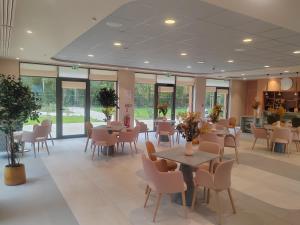 a dining room with tables and chairs and windows at DOMITYS - La Flânerie in Béthune