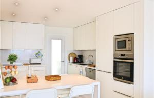 une cuisine avec des placards blancs et une table et des chaises blanches dans l'établissement Cozy Apartment In Tossa De Mar, à Tossa de Mar