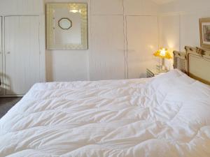 a large white bed in a white bedroom at Apple Tree Cottage in Charmouth