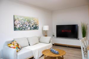 ein Wohnzimmer mit einem weißen Sofa und einem Flachbildfernseher in der Unterkunft MODERN 2 ROOM Apartment in Rüttenscheid in Essen