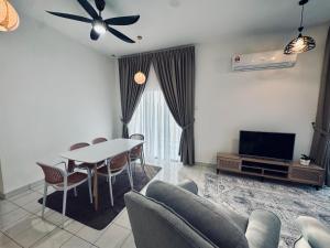 a living room with a table and chairs and a tv at Rimbayu 81 in Kampung Bota Kiri +3 photos