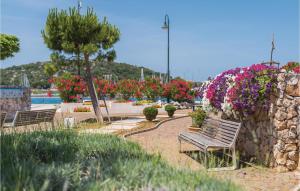 a park with benches and flowers and a wall at Three-Bedroom Apartment In Rogoznica in Rogoznica