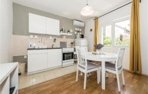 a kitchen and dining room with a table and chairs at Three-Bedroom Apartment In Rogoznica in Rogoznica