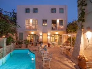 a house with a swimming pool in front of a building at Mythos Suites Boutique Hotel in Rethymno