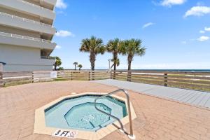 a swimming pool in the middle of a patio with palm trees at SeaSpray West 105- Gulf Front in Perdido Key