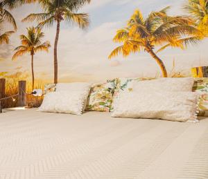 a bed with two pillows on it with palm trees at La petite maison de Nadette in Gandía