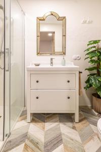 a white bathroom with a sink and a mirror at La petite maison de Nadette in Gandía