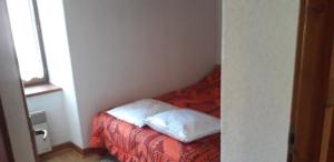 a small room with a bed with two pillows on it at Location appartement 6 personnes in Génos