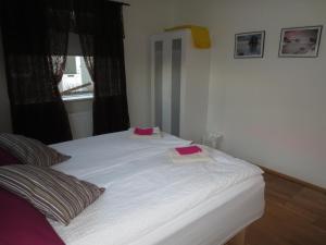 a white bed with two pink pillows on it at Teigur Guesthouse in Akranes