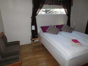 a bedroom with a bed with purple pillows and a window at Teigur Guesthouse in Akranes