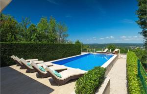 a swimming pool with lounge chairs next to a hedge at Villa Rosa Labin in Labin