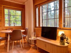 a living room with a tv and a table and windows at Hippu Holiday Home in peaceful location near Äkäslompolo in Äkäslompolo +20 photos