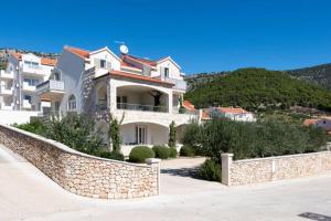 a large white house with a stone wall at Studio Apartments Regina in Bol