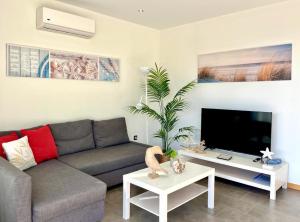 Una sala de estar con un sofá y un televisor. en Casa Tucan - two bedrooms, heated pool, city and ocean views, en Patalavaca