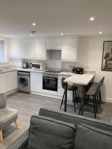 eine Küche mit einem Tisch und Stühlen sowie eine Küche mit weißen Schränken in der Unterkunft The Stage Door in Slough