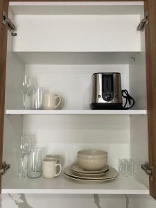 a cupboard with a microwave and plates and glasses at Porcelain Apartment in Rădăuţi +9 photos