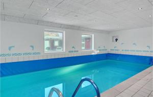 a large swimming pool in a room with a blue pool at Pet Friendly Home In Vejers Strand in Vejers Strand