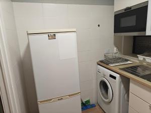 een kleine keuken met een witte koelkast en een wasmachine bij Lagoon House in Santiago do Cacém +1 foto