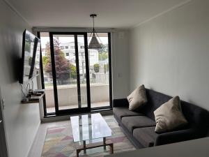 a living room with a couch and a glass table at Departamento amoblado, centrico in Temuco