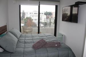 a bedroom with a bed and a large window at Departamento amoblado, centrico in Temuco