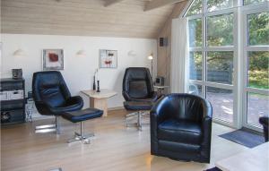 a room with three black chairs and a table and windows at Holiday Home Guldvangen Nørre Nebel I in Lønne Hede