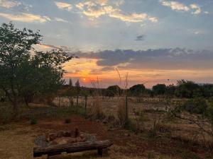 un banc dans un champ avec le coucher du soleil en arrière-plan dans l'établissement Lekker Plekkie Farm Cottage, à Hekpoort