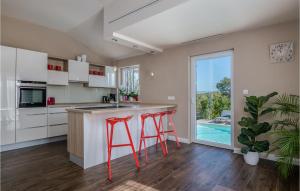 a kitchen with red stools at a kitchen counter with a pool at 4 Bedroom Gorgeous Home In Krk in Krk