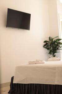 a table with a tv on a white wall at Luna Nuova Gallipoli Comfort & Suites in Gallipoli