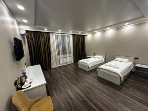 a hotel room with two beds and a television at DOSTYK Hotel in Zyryanovsk