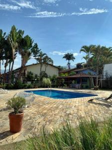 a swimming pool with chairs and a house and palm trees at Cana Caiana Casa in Paraty