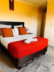 une chambre avec un grand lit recouvert d'une couverture rouge dans l'établissement Mnceba Mbotyi cottage, à Lusikisiki 5 autres photos