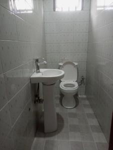 a white bathroom with a toilet and a sink at Sour sop Guest House in Kampala