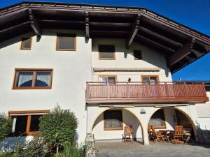 a large white building with a balcony with tables and chairs at Ferienwohnung Schaller in Feistritz an der Drau