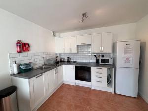 Una cocina con gabinetes blancos y un refrigerador blanco. en East Down, en Glastonbury