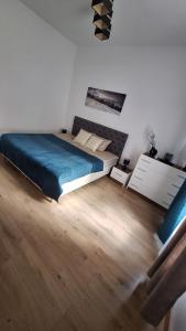 a bedroom with a bed with blue sheets and a wooden floor at Apartamenty Droga na Śnieżkę in Karpacz