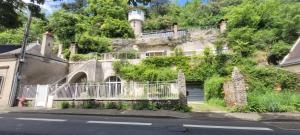 una vecchia casa su una collina con una torre dell'orologio di Troglodyte Loft a Saint-Étienne-de-Chigny