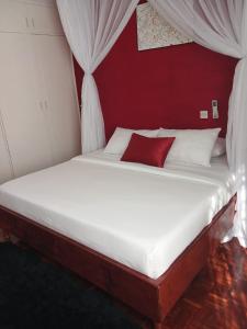 a bed in a room with a red wall at Annodas Homes Milimani in Kisumu +1 photo