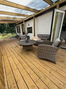 a patio with a couch and chairs on a deck at Bosrijk chalet Veranda, Honden in Doornspijk