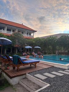 a group of people sitting around a swimming pool at New Mekar Jaya Hotel in Legian
