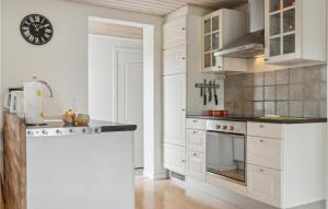 a kitchen with white cabinets and a stove top oven at Beautiful Home In Væggerløse With Wifi in Marielyst +16 photos
