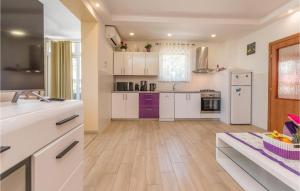a large kitchen with white cabinets and purple appliances at Holiday Home Zadar 37 in Kakma