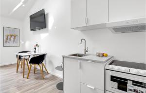 a white kitchen with a sink and a table at 1 Bedroom Amazing Apartment In Svaneke in Svaneke