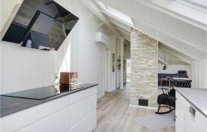 a kitchen with white cabinets and a stone fireplace at Four-Bedroom Holiday Home In Blavand in Blåvand